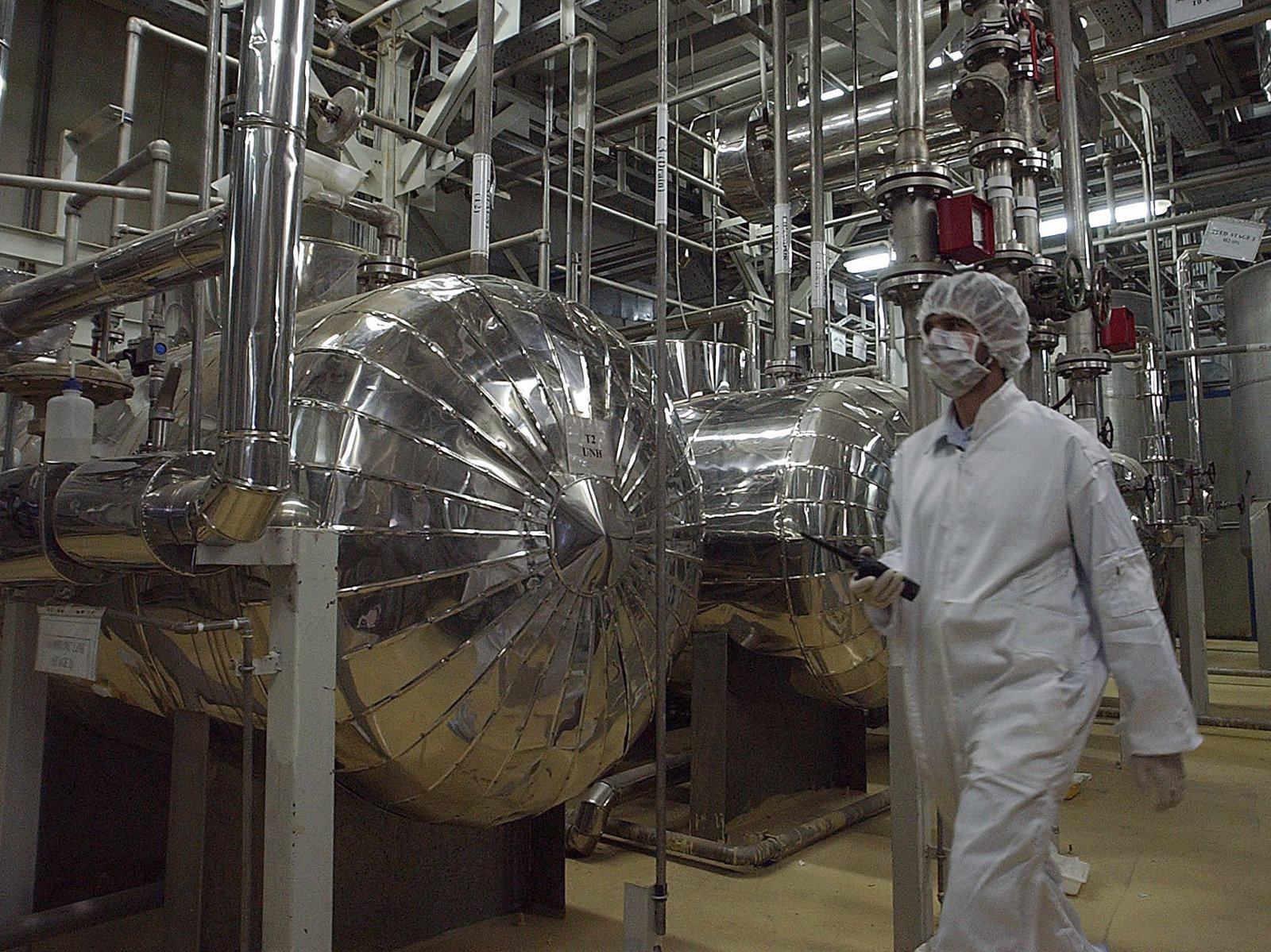 An Iranian security official in protective clothing walks through a uranium conversion facility in 2005. Iran says it is now enriching uranium above the limit set in the 2015 nuclear deal. Vahid Salemi/AP